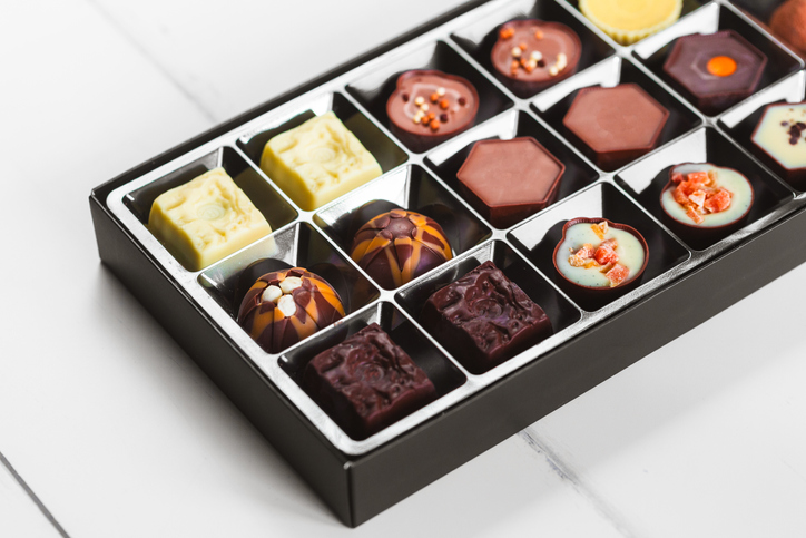 Various types of decorative chocolates within an ornate box.