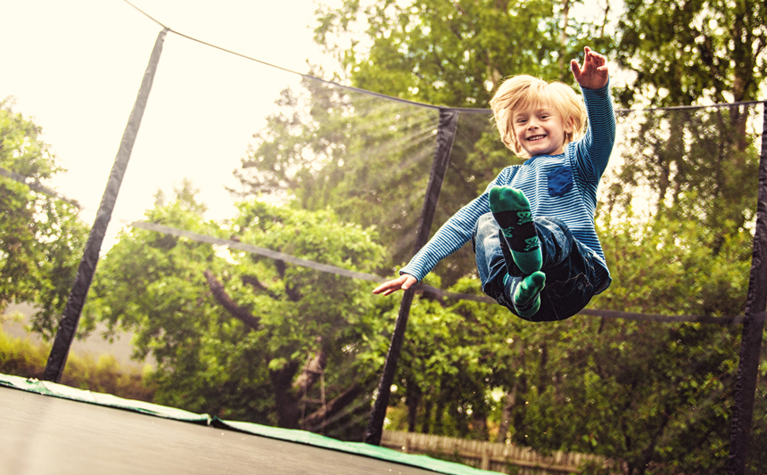 A young boy bounces on a trampoline.