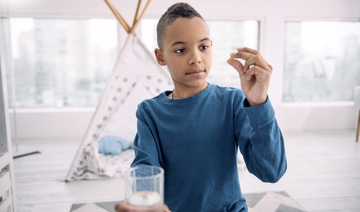 Young boy holds up a pill