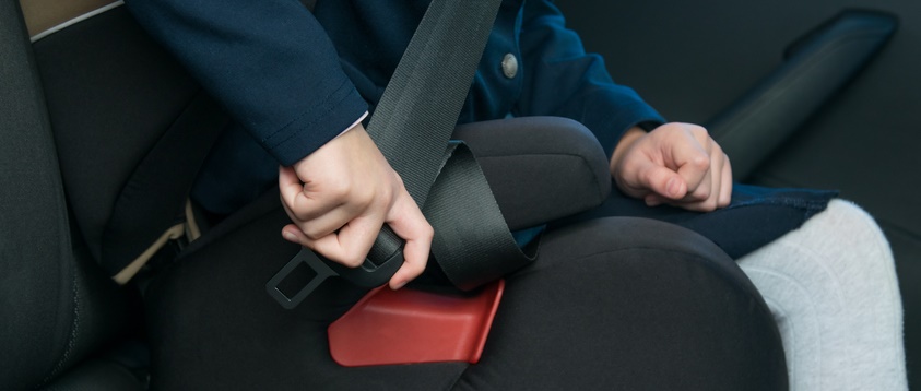 A child buckles their car seat.