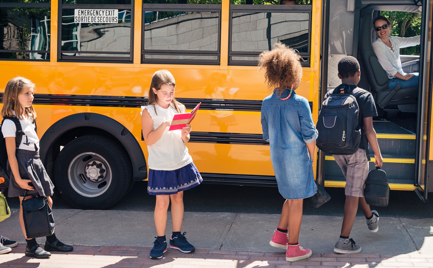 Children in a line board a school bus.