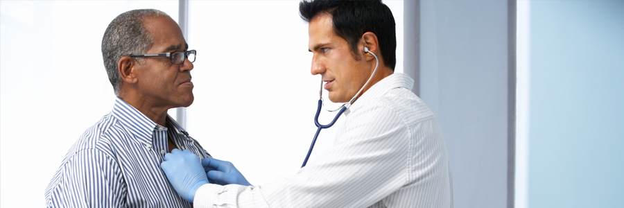 A doctor listens to a man's heart using a stethoscope.