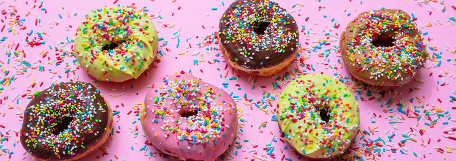 A row of colorful donuts on a pink background.