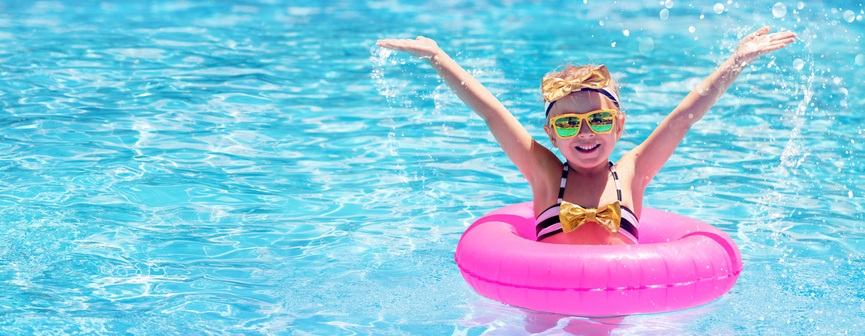 Young girl swims in a pool with pink tube.