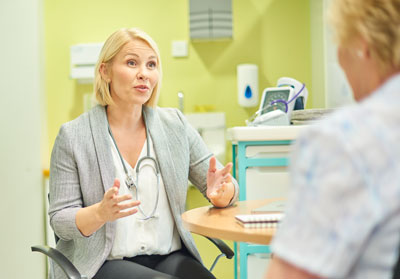 A doctor talks with a patient in the examination room.
