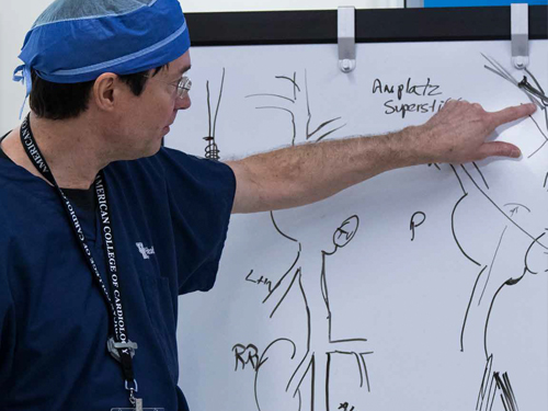 Dr. John Gurley gestures toward a whiteboard.