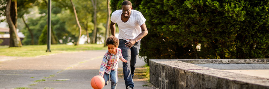 A father and his young son play with a basketball.