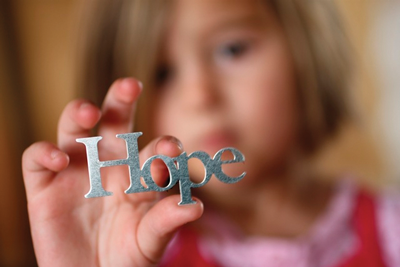 A girl holds letters spelling "hope."