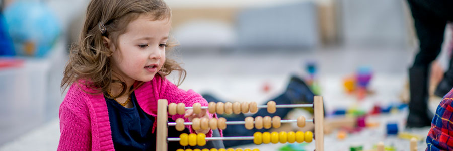 A little girl plays with counting beads (abacus).