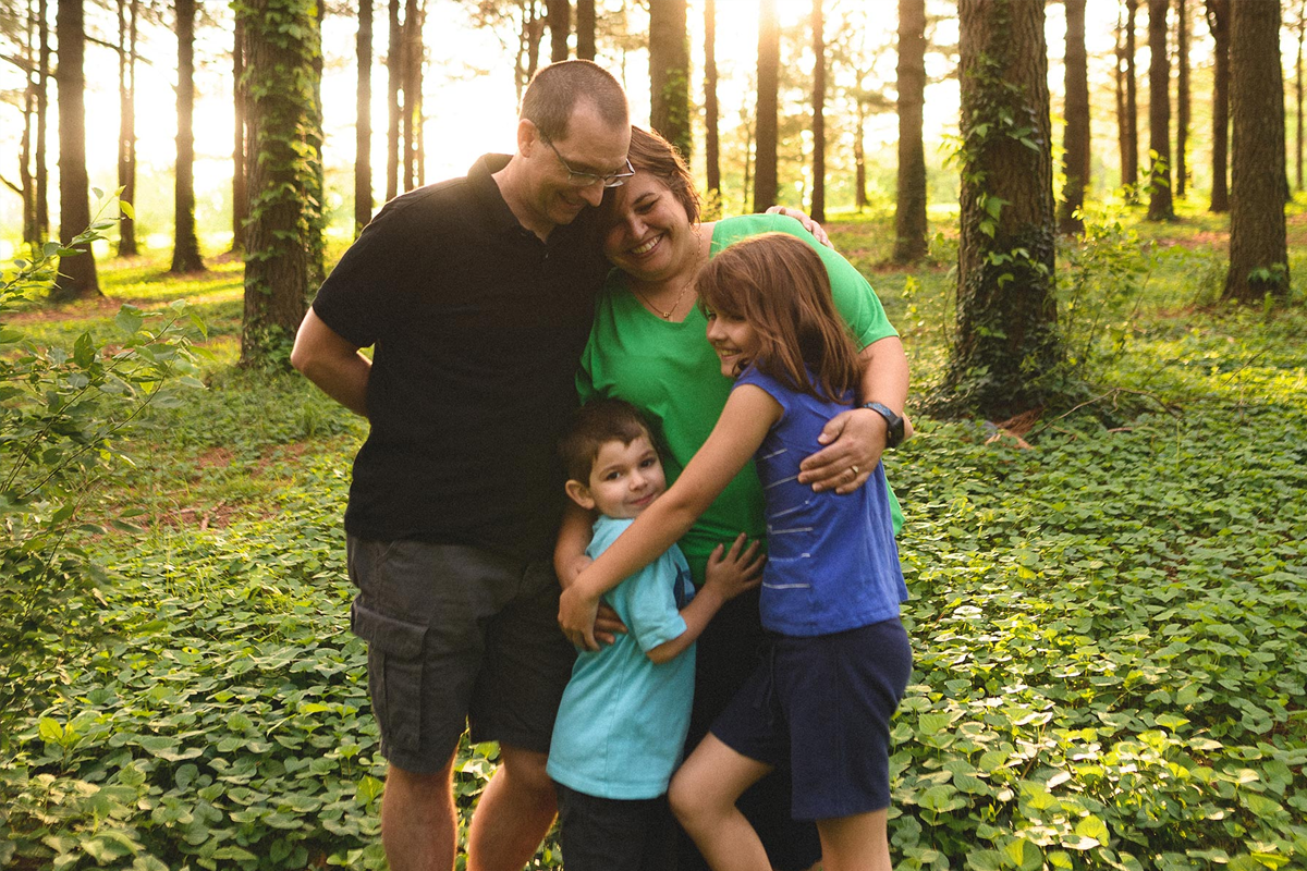 The Middleton family enjoys a hug outdoors under the trees.