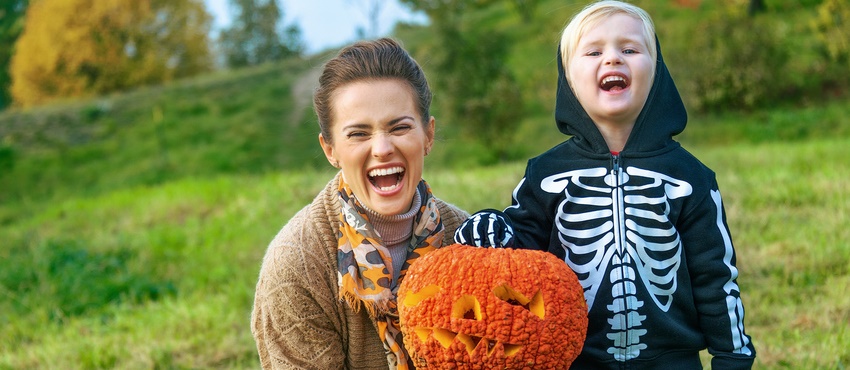 A mother and her young son hold a carved pumpkin.