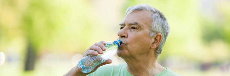 A senior man drinks from a water bottle.