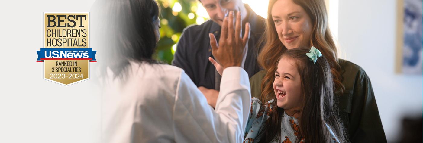 A little girl gives her provider, a female wearing a white coat, a high five while laughing. Her smiling parents look on. The image also includes a badge that reads U.S. News and World Report Best Children's Hospitals, Ranked in Three Specialties, 2023–2024.