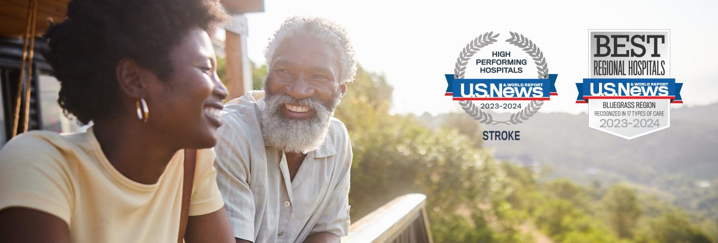 An African American man and woman smile at one another as they lean against a deck railing. Superimposed on the image are two badges: One reads, "US News & World Report High Performing Hospitals, 2023–2024, Stroke." The other reads, "US News & World Report Best Regional Hospitals, Bluegrass Region, Recognized in 17 Types of Care, 2023–2024."