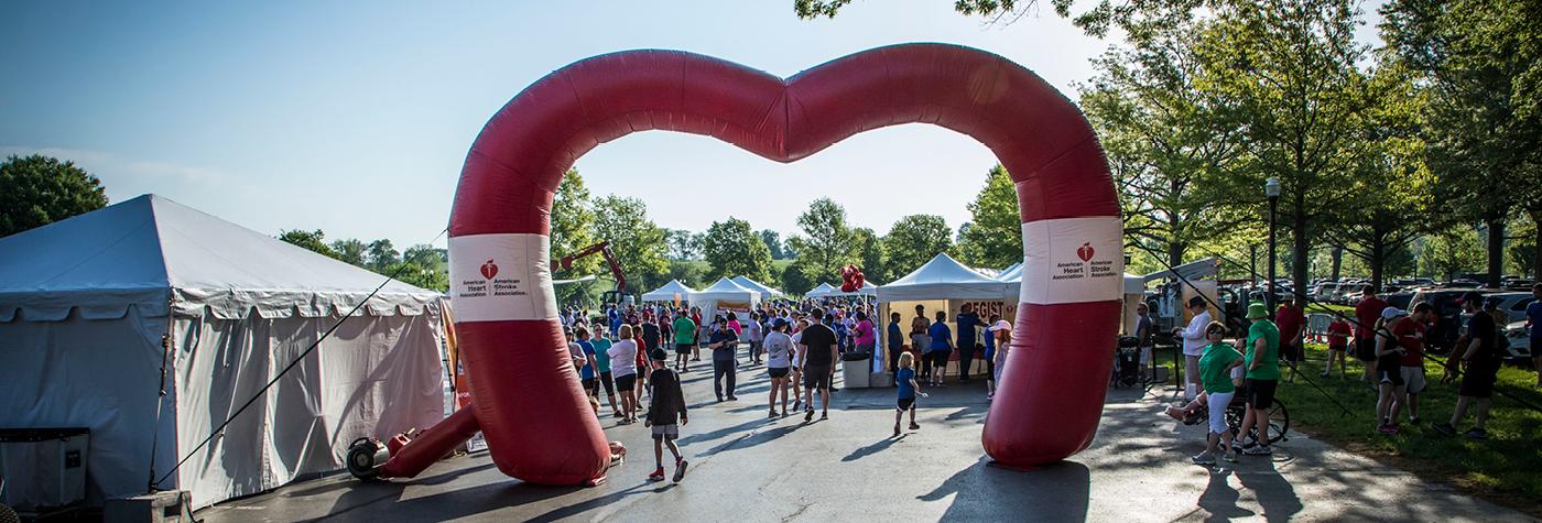 People are seen walking through an inflatable archway in the shape of a heart.
