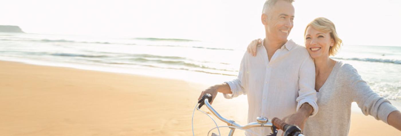 A middle-aged couple on the beach with bicycles.