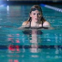 Alayna Benningfield, in a swimming pool, rises her head out of the water for air.