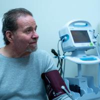 Ron Kelly smiles while having his blood pressure monitored during a visit at UK HealthCare.