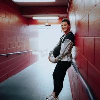 Arin holds a soccer ball next to her baby bump while leaning in the hallway that leads to the soccer field she plays at.
