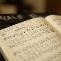 A hymnal opened to How Great Thou Art with dates written on the page