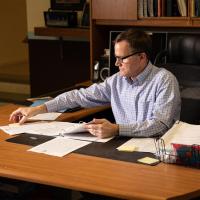 Bill Crawford sitting at a desk, examining paperwork