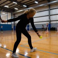 Donna prepares to serve the ball at a pickleball game.