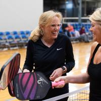 Donna smiles and laughs with a competitor on the other side of the net.