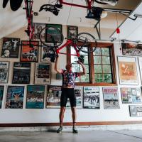 Doug lifts his bike above his head to hang it up on hooks in his garage.