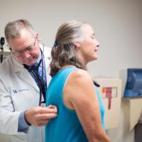 Dr. Mullett listens to a patient's heartbeat with his stethoscope.