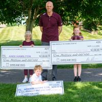 A.W. proudly poses with his children, each of whom is holding a large $1 million check.