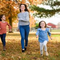 A candid photo of the three Shaughnessy girls running through the autumn leaves together, with Kailey in the lead.
