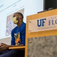 A candid photo of Michael sitting down while giving a presentation at the University of Florida.