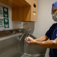 Dr. Kim washes his hands at a sink outside of the operating room.