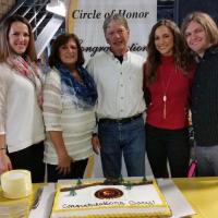A photo of the Montgomery family smiling and posing in front of a cake for Gary.