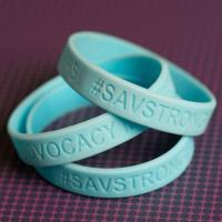 A close up of light blue silicone bracelets imprinted with #SAVSTRONG