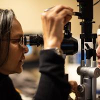 Dr. Capoor looks through a slit lamp into a patient's eyes.