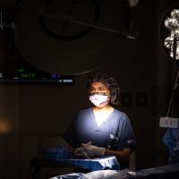 Dr. Capoor stands in a dim operating room with a light shining on her.