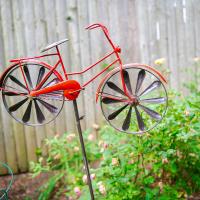 A red bicycle garden ornament. The wheels are wind spinners.