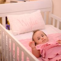 Wylie looks up as she lays in her all-pink crib.