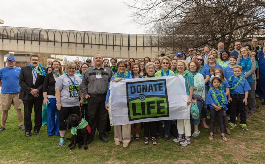 A group of UK HealthCare employees stand with a Donate Life banner.