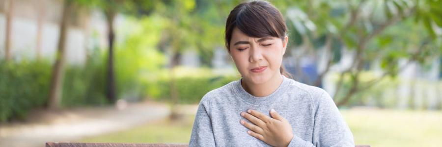 A young woman with heartburn presses her hand to her chest.