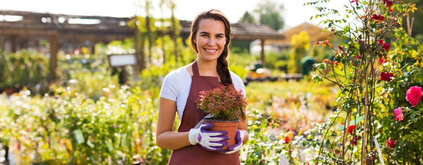 Woman smiles while holding a flower pot.