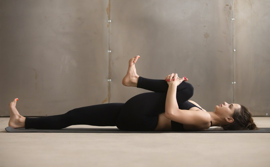 A woman does stretching exercises on the floor.