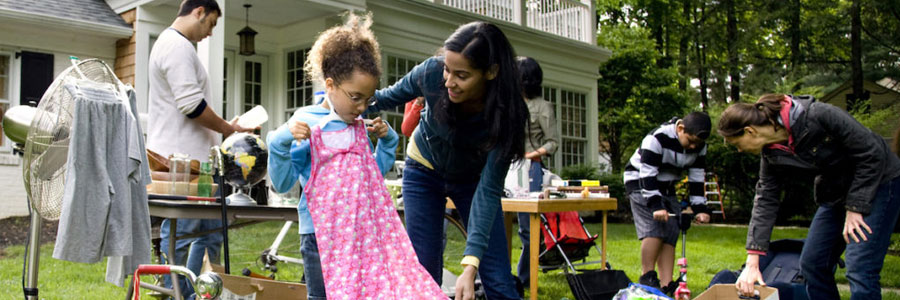 A mother shops with her young daughter at a yard sale.
